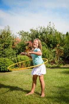 Active child - girl dancing with hoop outdoor in sunny backyard