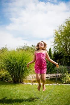 Active child - happy girl jumping with skipping rope outdoor, copy space