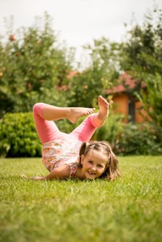 Smiling little child having fun lying on grass - outdoor in backyard