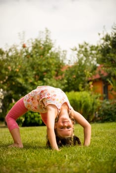 Sporting on grass - smiling little child making bridge outdoor in backyard