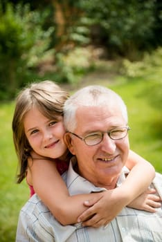 Outdoor lifestyle portrait of grandchild hugging grandfather