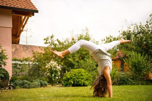 Active childhood - little child making handstand outside in backyard
