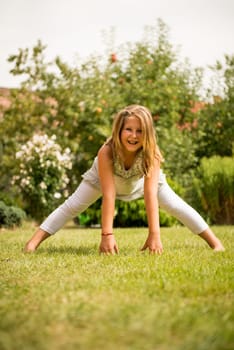 Sporting on grass - smiling little child exercising outdoor in backyard