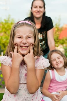 Child with cheeke expression - mother and sister in background