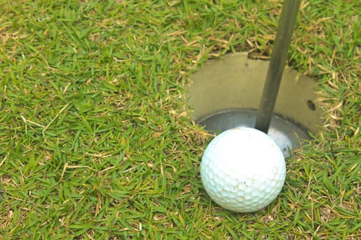 Golf ball on grass lip of the hole