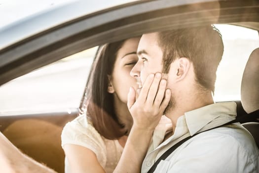 Couple in love - woman kissing man in car while driving