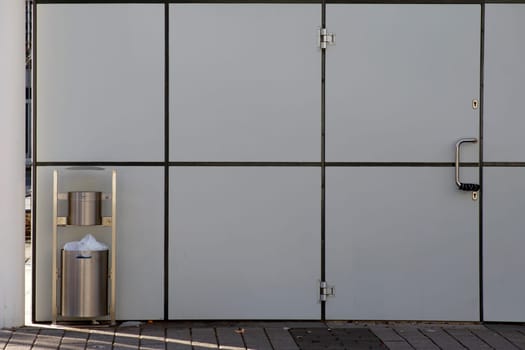The photograph of a trash can on a modern house wall.