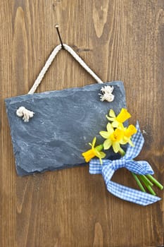 Small slate and fresh daffodils on a rustic background