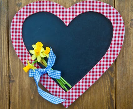Heart-shaped table and fresh daffodils on a rustic background