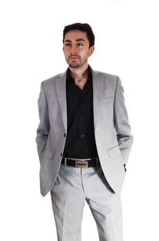A tall handsome businessman standing for white background in a gray .suit with his hands in his pocket..