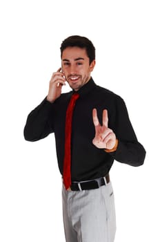 A young businessman in a black shirt and tie talking on his cell phone.making a victory sign..