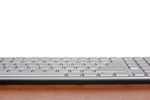 Silver computer keyboard on the wooden desk with copy-space for your text