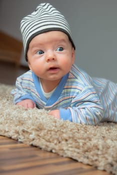 Studio portrait of a happy 2 months old baby boy at home on the floor.