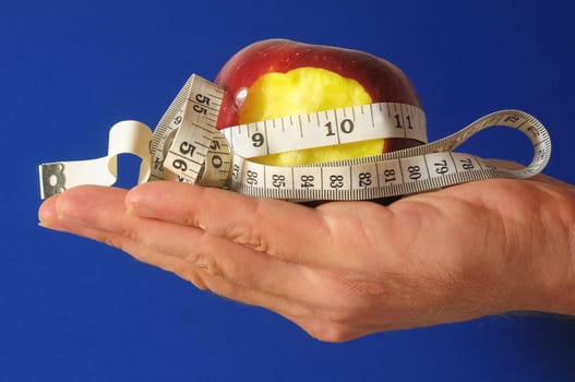 Bitten Diet Apple and Meter the Hand on a Colored Background
