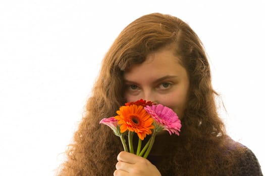 A young pretty woman holds a bouquet of flowers in her hand and smells it