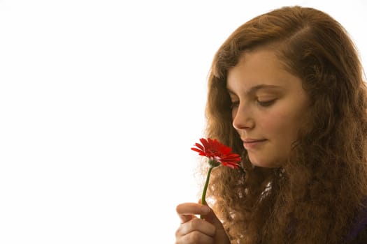 Eine junge hübsche Frau hält eine Blume in der Hand und riecht daran