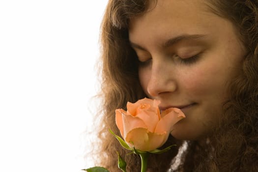 A young pretty woman holds a rose in her hand and smells it