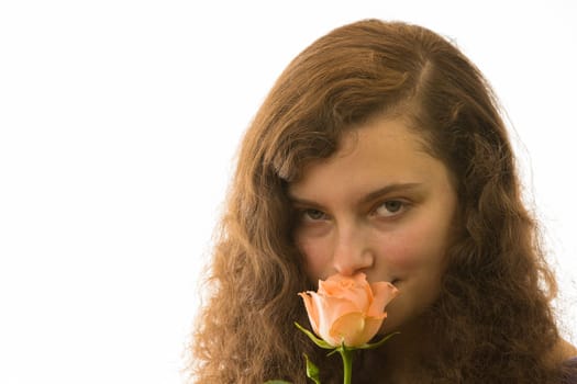 A young pretty woman holds a rose in her hand and smells it