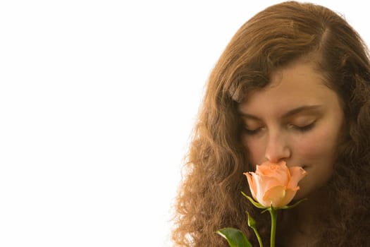 A young pretty woman holds a rose in her hand and smells it