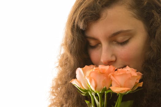 A young pretty woman holds a bouquet of roses in her hand and smells it