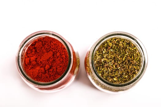 Oregano and paprika powder in a glass pot.