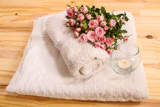Bunch of small pink Roses on towels with a candle, close up.