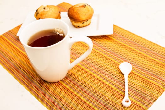 Vanilla with chocolate chips Muffins on a white plate with  a cup of tea.