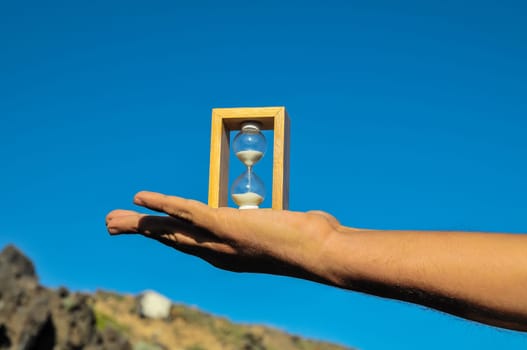 Time Concept White Sand Hourglass on the Volcanic Rocks