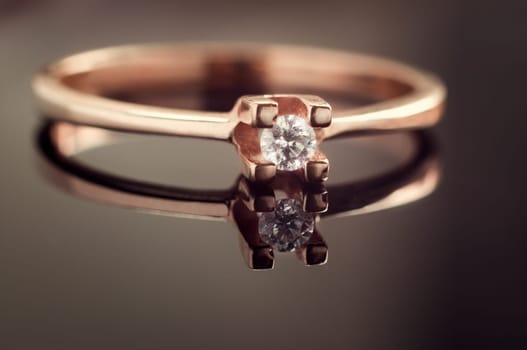Golden wedding ring with a diamond,on reflective glass surface