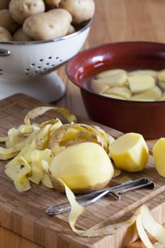 Potatoes and potato peelers on cutting board
