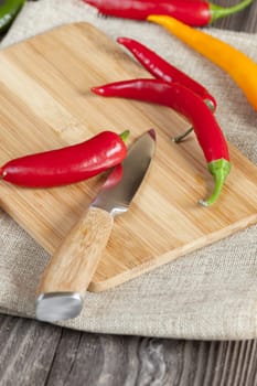 Chili peppers on cutting board with knife and text space