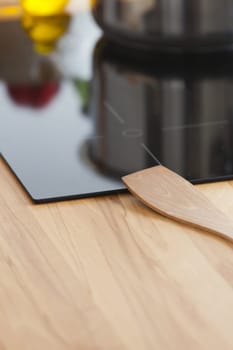 Wooden spoon lies on ceramic hob in kitchen