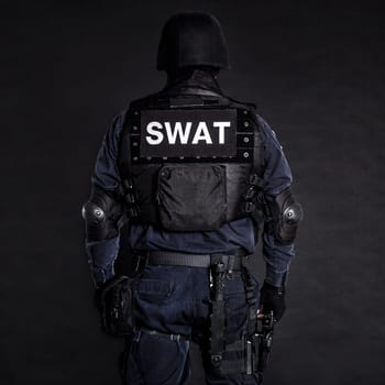 Special weapons and tactics (SWAT) team officer on black background shot from behind