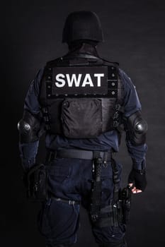 Special weapons and tactics (SWAT) team officer on black background shot from behind