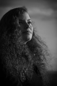 The face of a young pretty woman in the sunlight in black and white