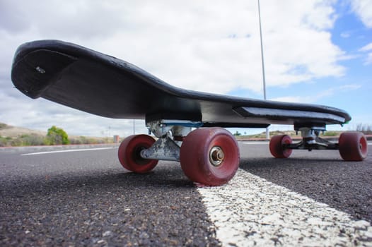 Vintage Style Longboard Black Skateboard on an Empty Asphalt Desert Road