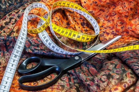 Tailor measuring tape and scissors on patterned fabric