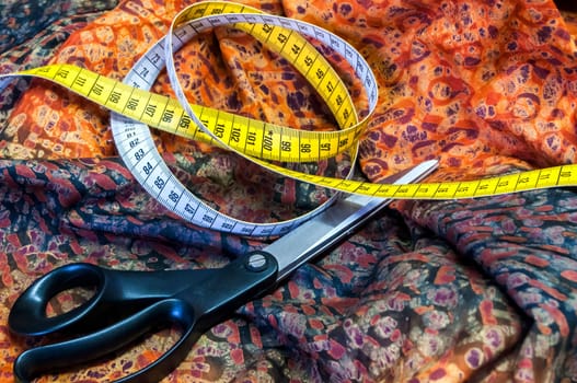 Tailor measuring tape and scissors on patterned fabric