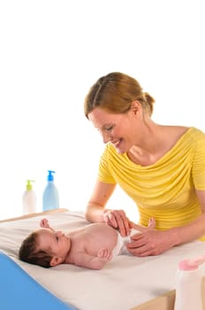Mother with her newborn baby does infant care at the changing table,exposed against a white background.