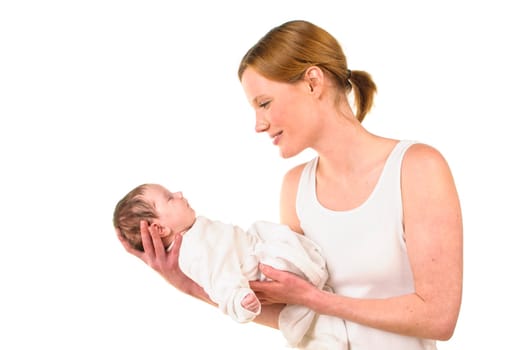 An adult woman with a white shirt tenderly holds an infant dressed in white in her arms,exposed against a white background.