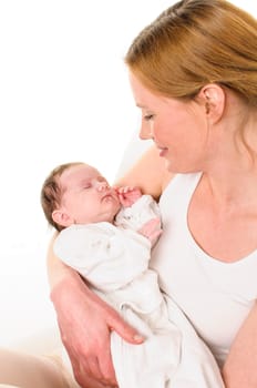 An adult woman with a white shirt tenderly holds an infant dressed in white in her arms,exposed against a white background.