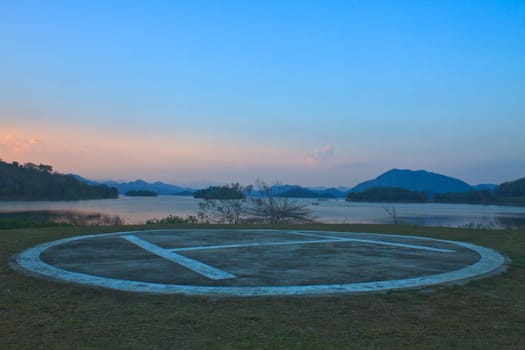 Helipad area for helicopter parking near lake on sunset