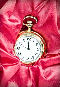 Old styled gold pocket watch on scarlet silk
