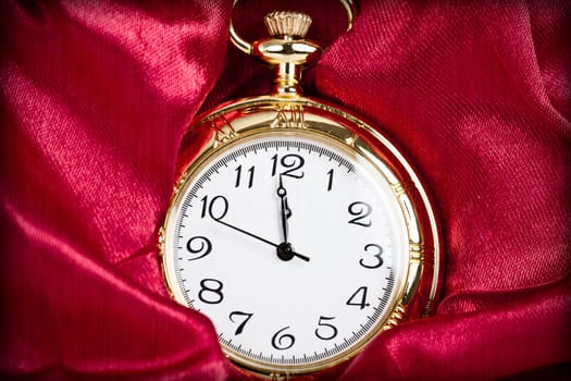 Old styled gold pocket watch on scarlet silk