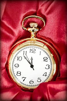 Old styled gold pocket watch on scarlet silk