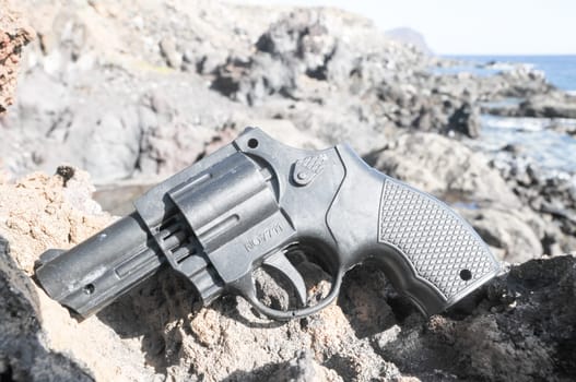 Plastic Revolver Gun Toy on the Volcanic Rocks
