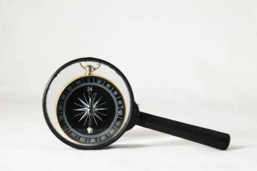 Orientation Concept - Analogic Compass and Loupe on a White Background