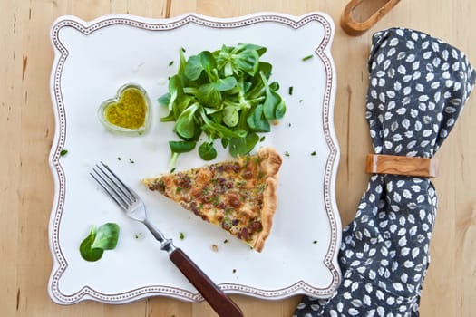 Square plate with quiche Lorraine and lamb's lettuce