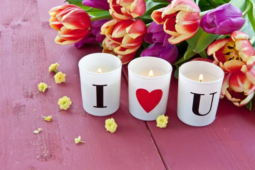Fresh tulips and candles on red table