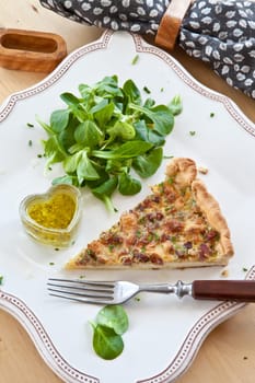 Square plate with quiche Lorraine and lamb's lettuce